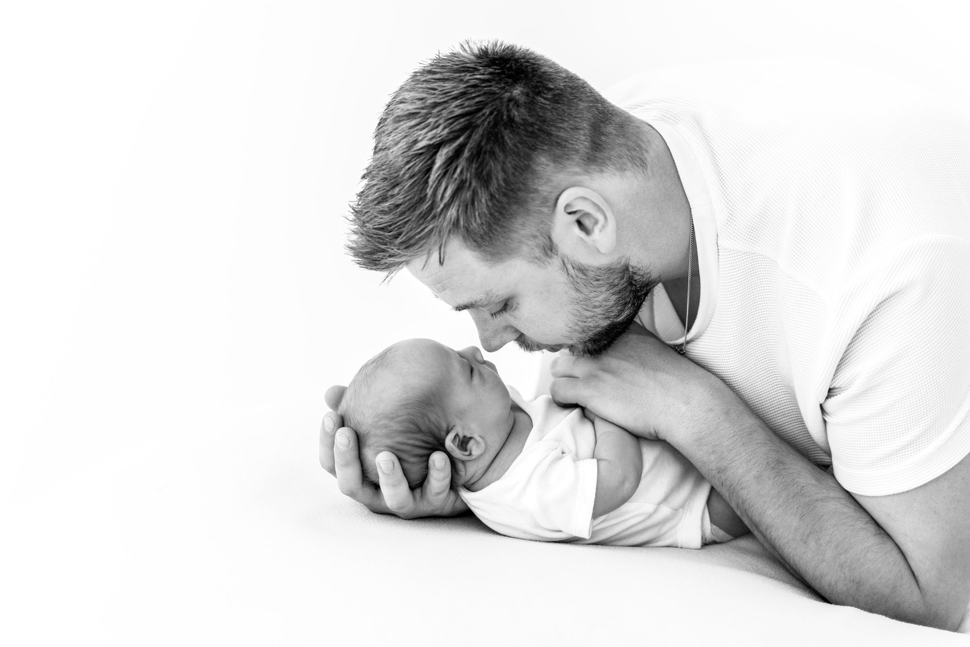 father cradles infant during session with newborn photograph