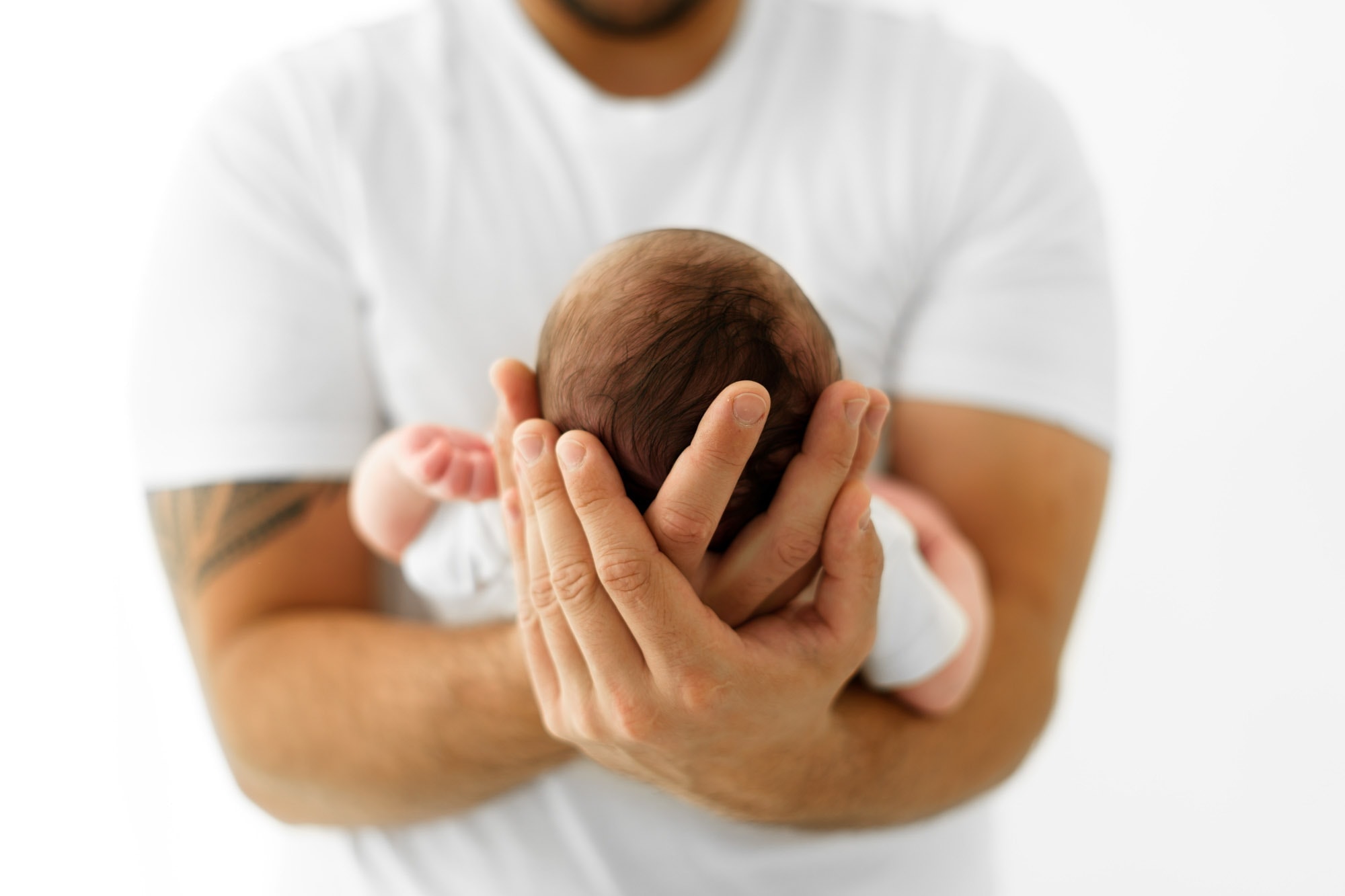 newbornb held in fathers hands toward camera during newborn photographer norwich session