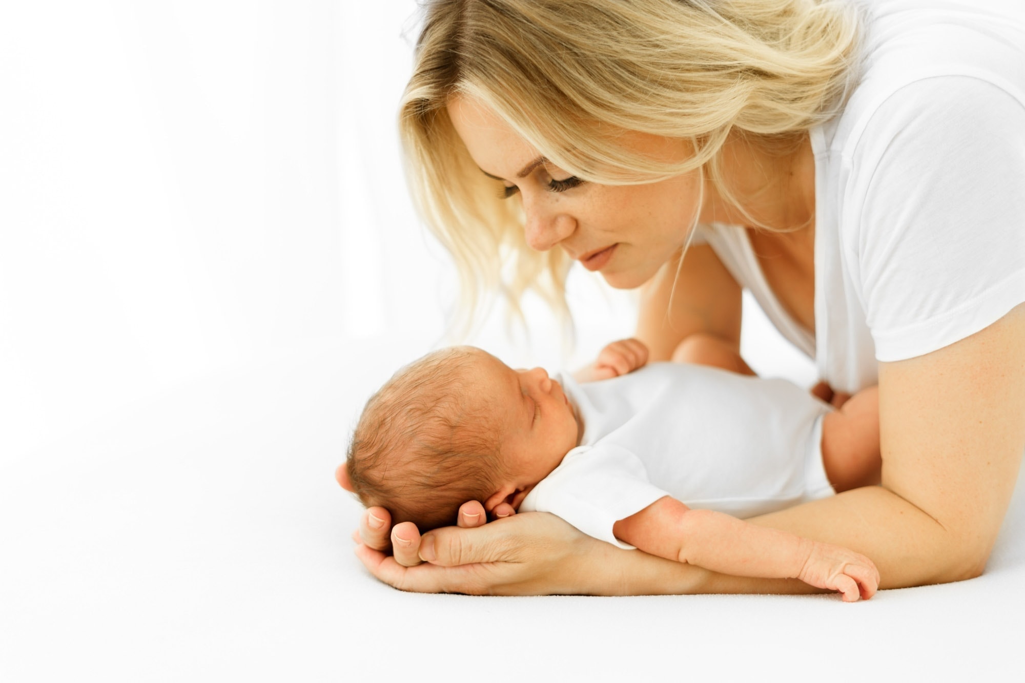 natural newborn photography in norwich of mother leaning over her newborn baby