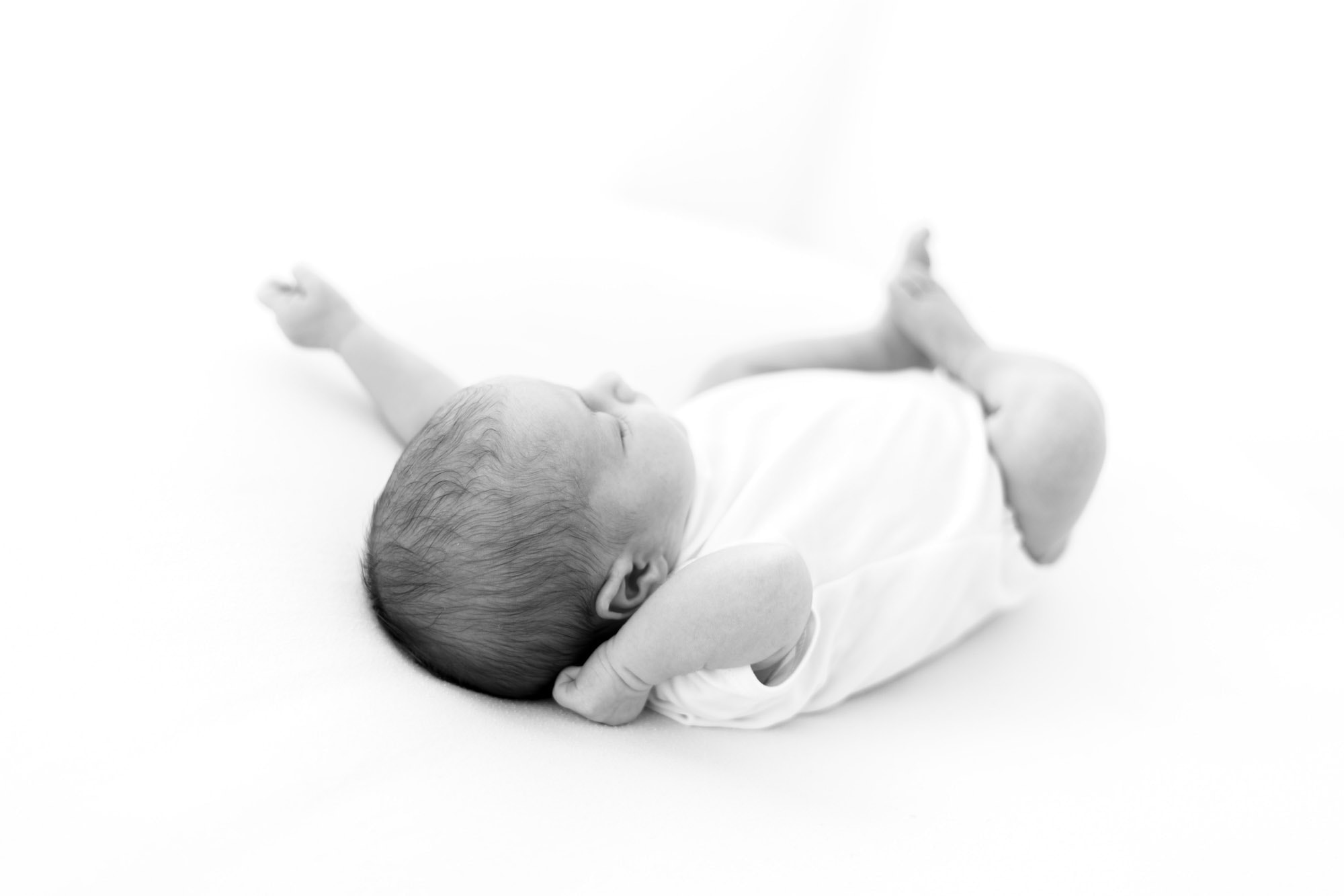 newborn photographer norwich captures baby stretching on white background