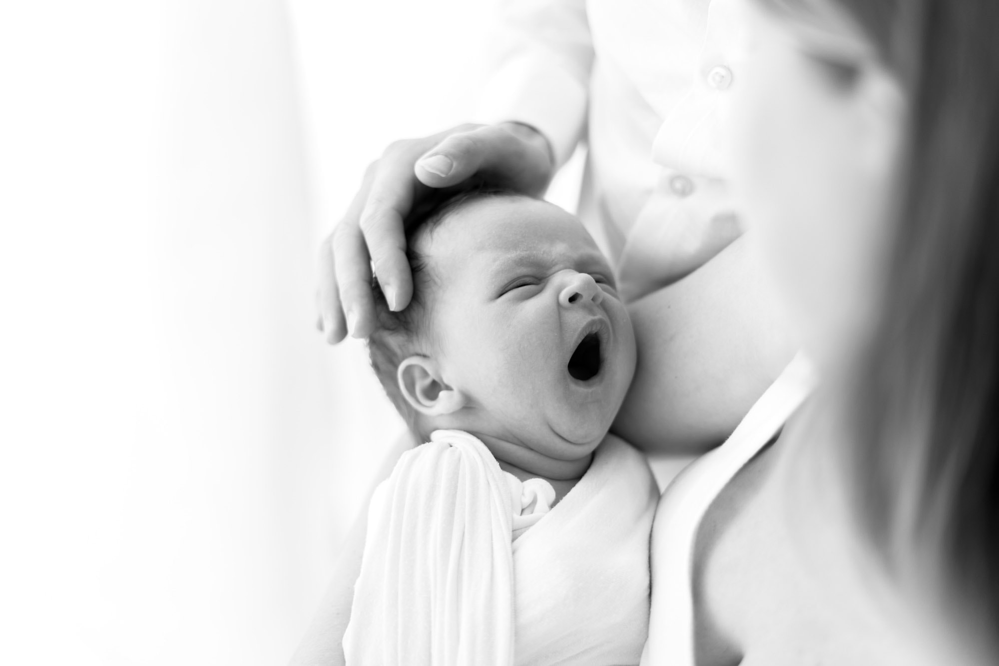 norwich newborhn photographer photographs baby held by dad whilst yawning